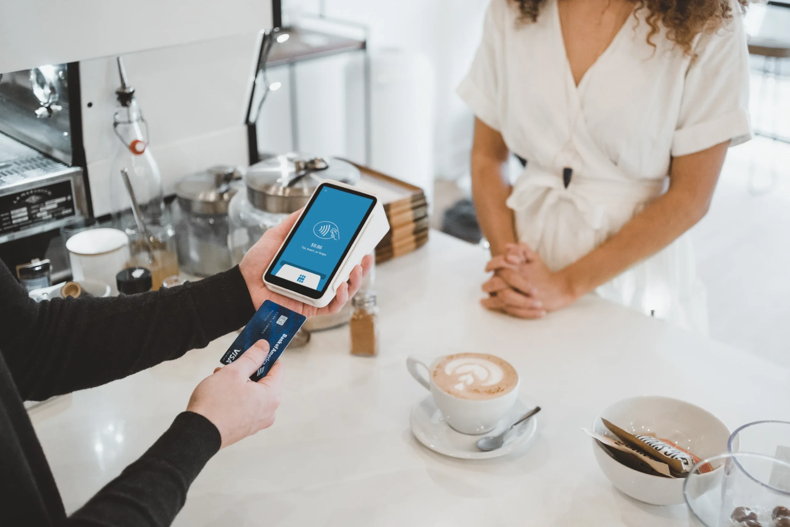 A person making a contactless payment with a smartphone at a café.