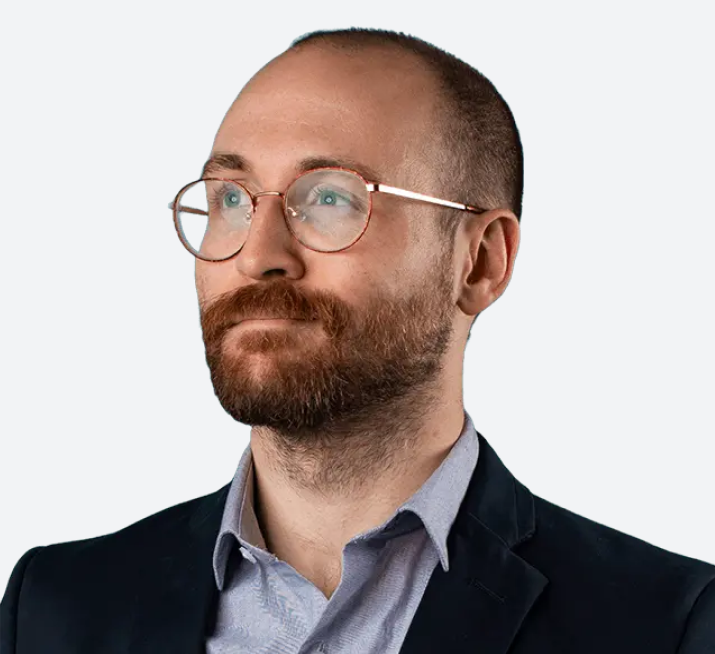 Portrait of a thoughtful man with glasses and beard in formal attire.