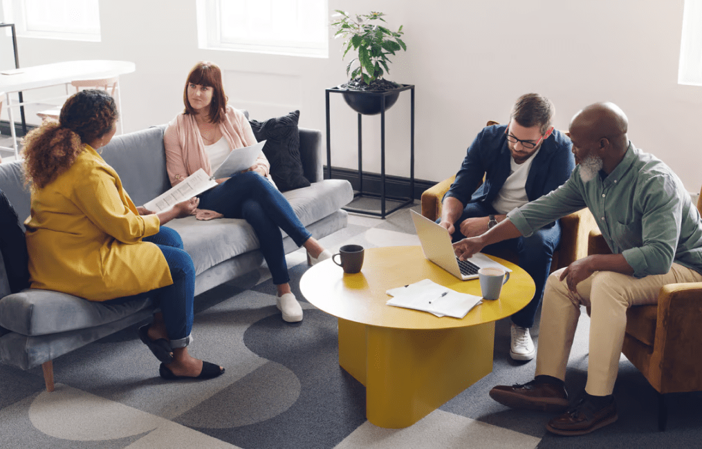 Four people having a casual meeting in a modern office lounge.