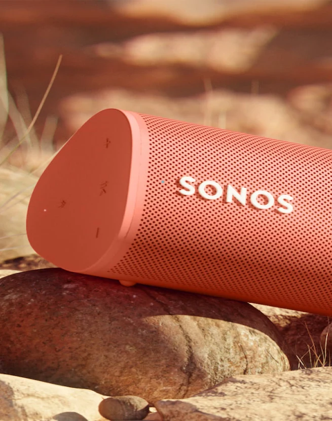 Close-up of a red Sonos portable speaker on a rock.