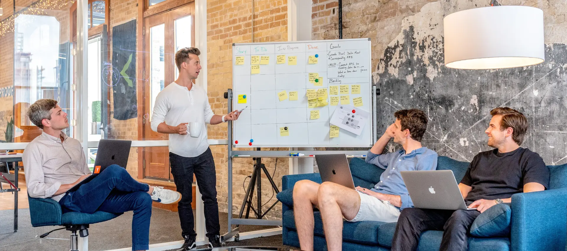 Team collaborating around a whiteboard with sticky notes in a casual office.