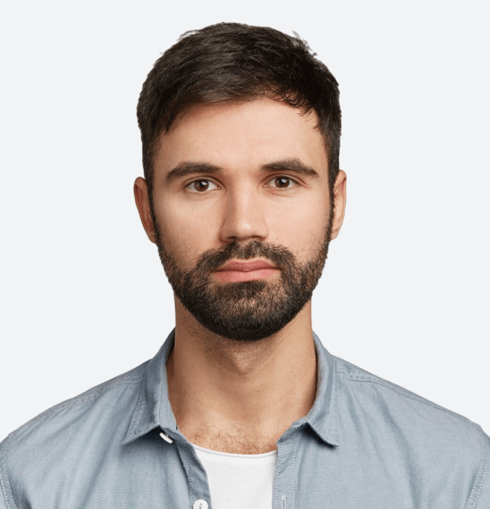 Serious young man with a beard in a light blue shirt against a white background.