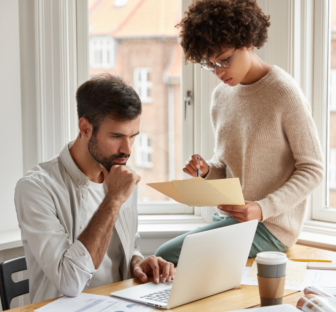 Two colleagues discussing documents in a bright office space.