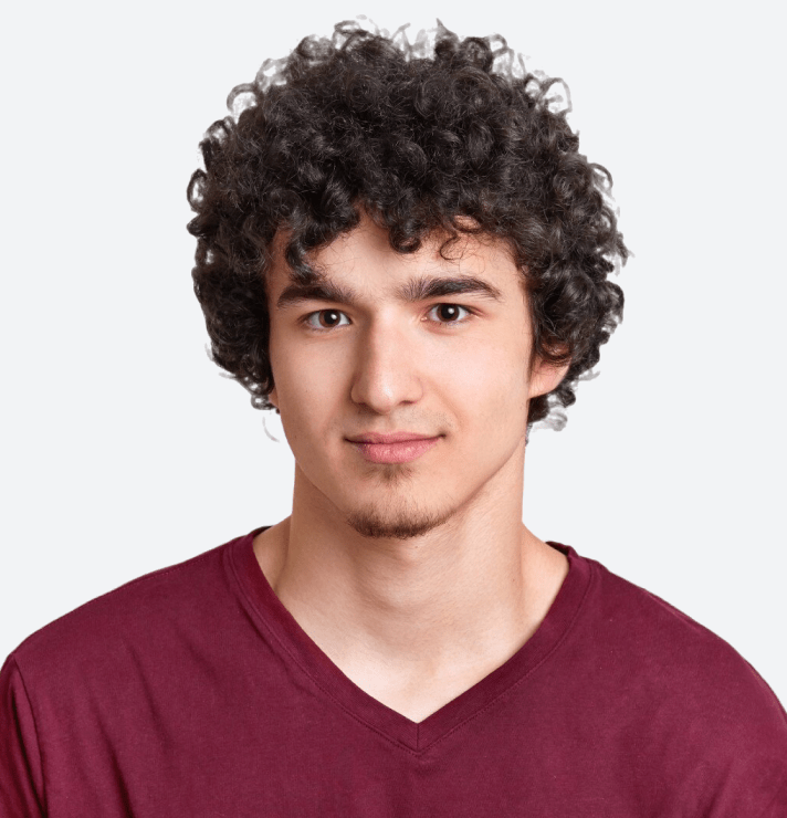 A young man with curly hair wearing a maroon V-neck shirt.