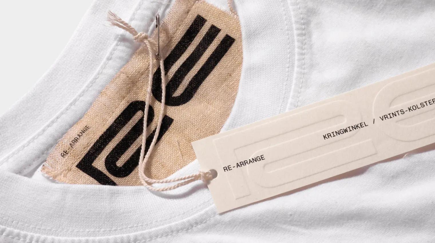 Close-up of a white garment with branded tags and a string.