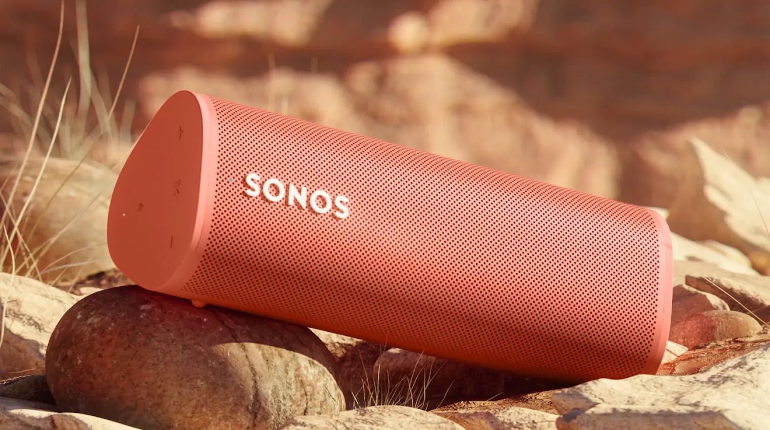 Close-up of a pink Sonos portable speaker on a rocky surface.