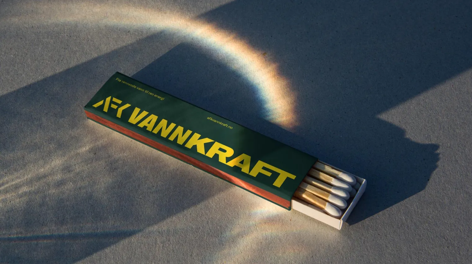 A box of matches casting a vivid circular rainbow shadow on a surface.