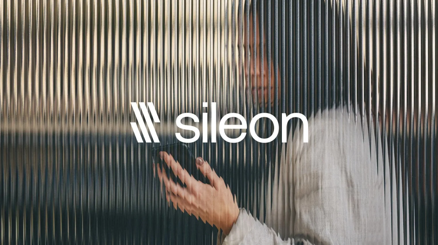 Person using a smartphone behind a textured glass with 'sileon' logo.